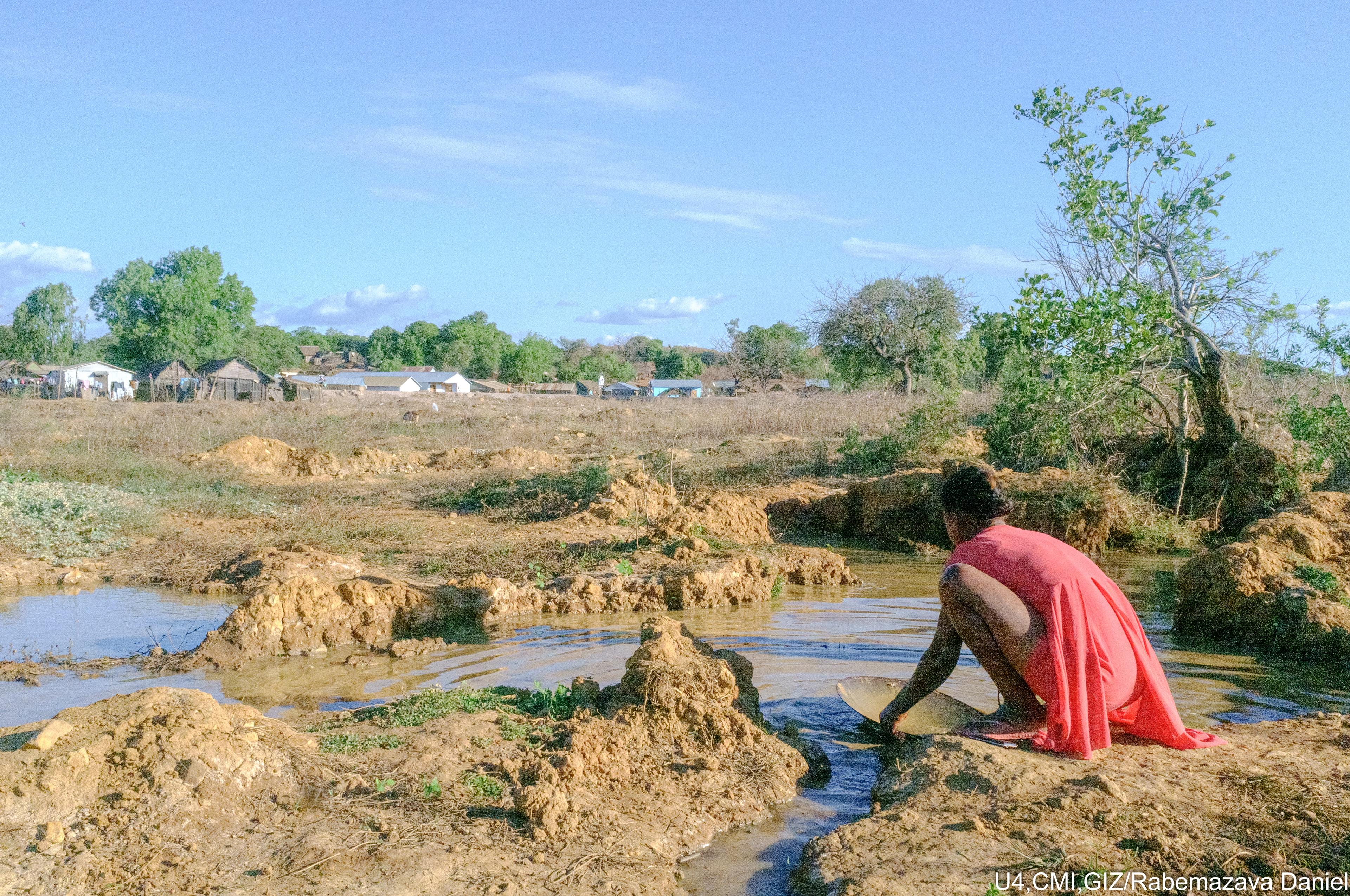 Looking for gold in a river by a village.