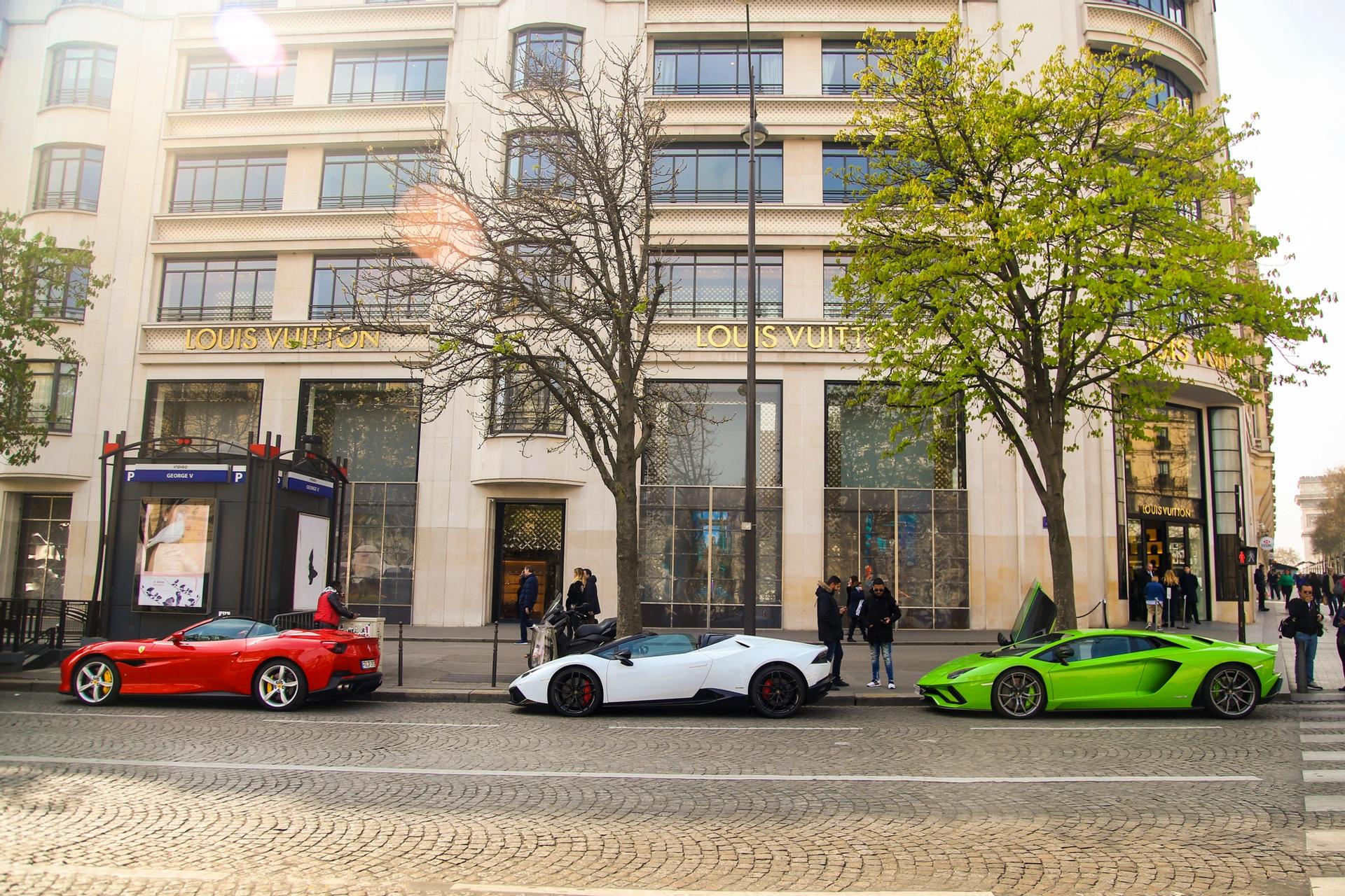 Trois voitures de sport garées devant le magasin Louis Vuitton sur les Champs-Élysées, Paris