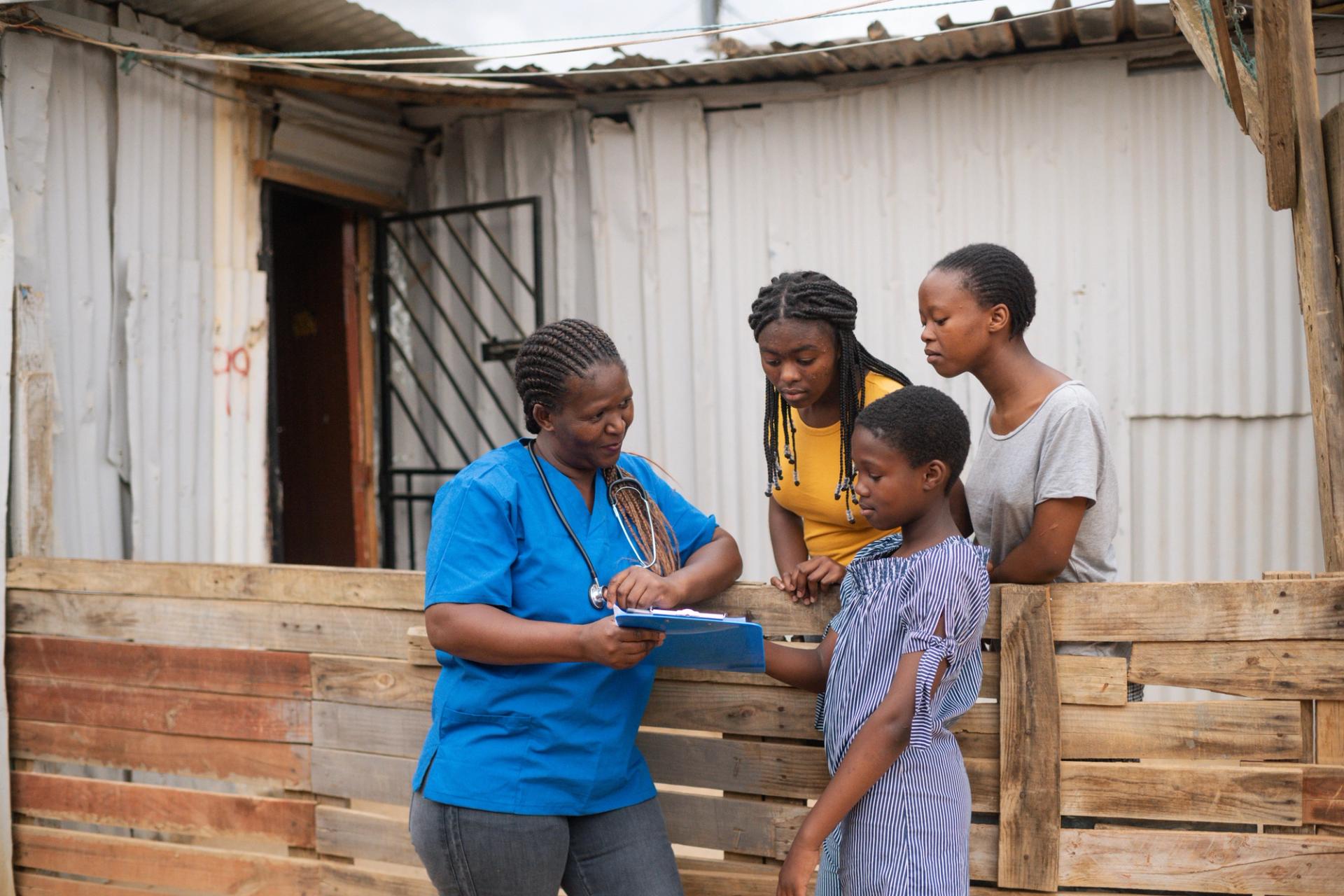 Community nurse talking to three teenage girls in an informal settlement, Stellenbosch, South Africa.