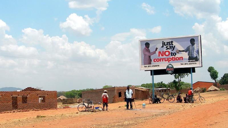 Countryside with scattered housing and a billboard with the message "Just say NO to corruption"