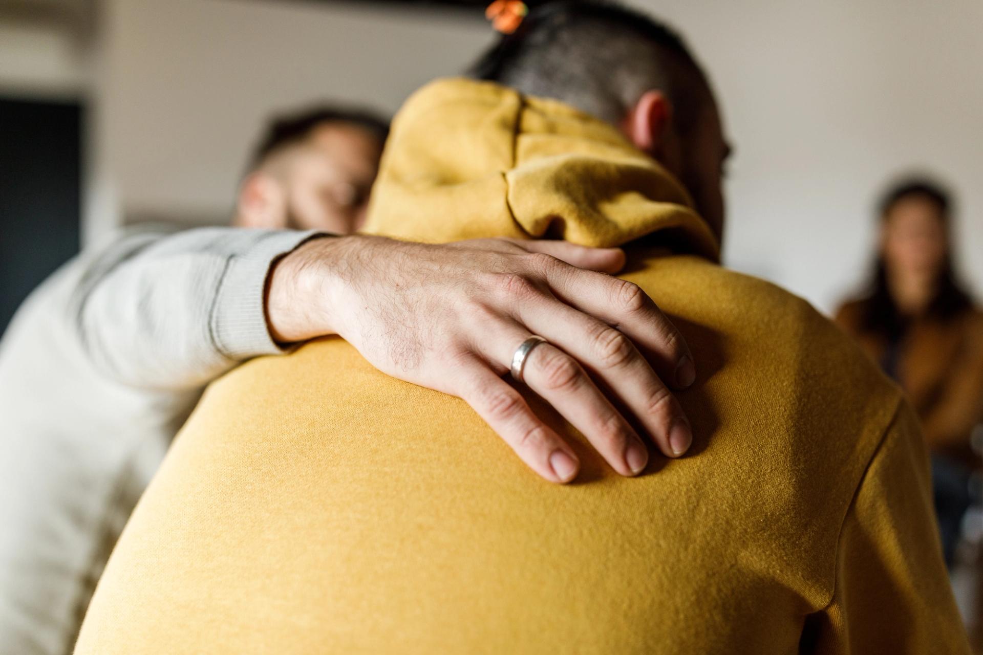 Close up shot of compassionate man embracing his friend.