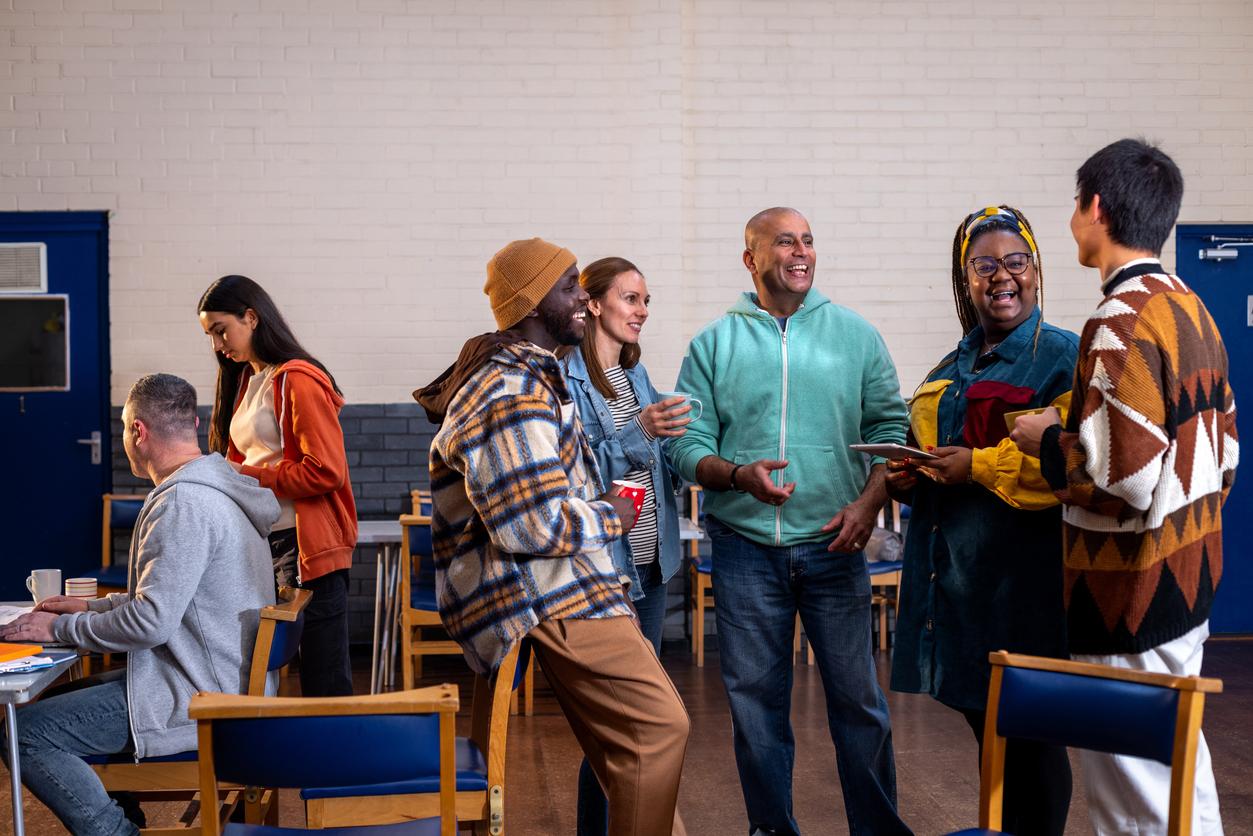 A group of adults standing in a circle and talking to each other