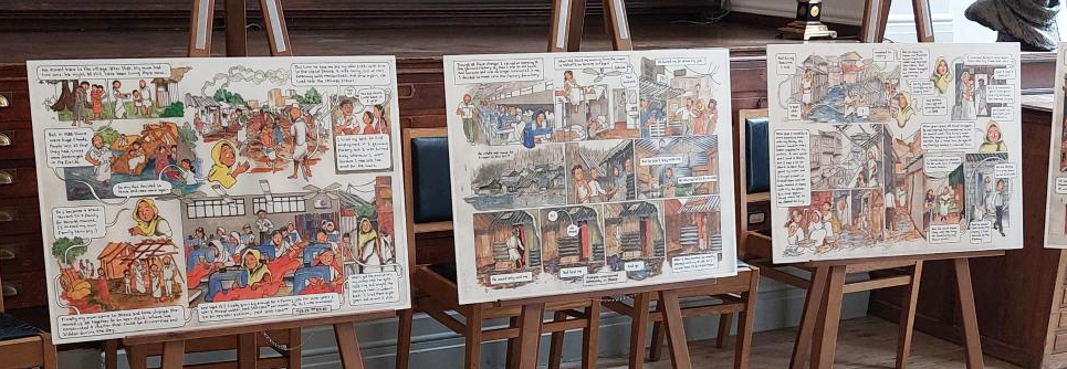 Three multi-panel storyboards from graphic novels displayed on easels at the comic con.