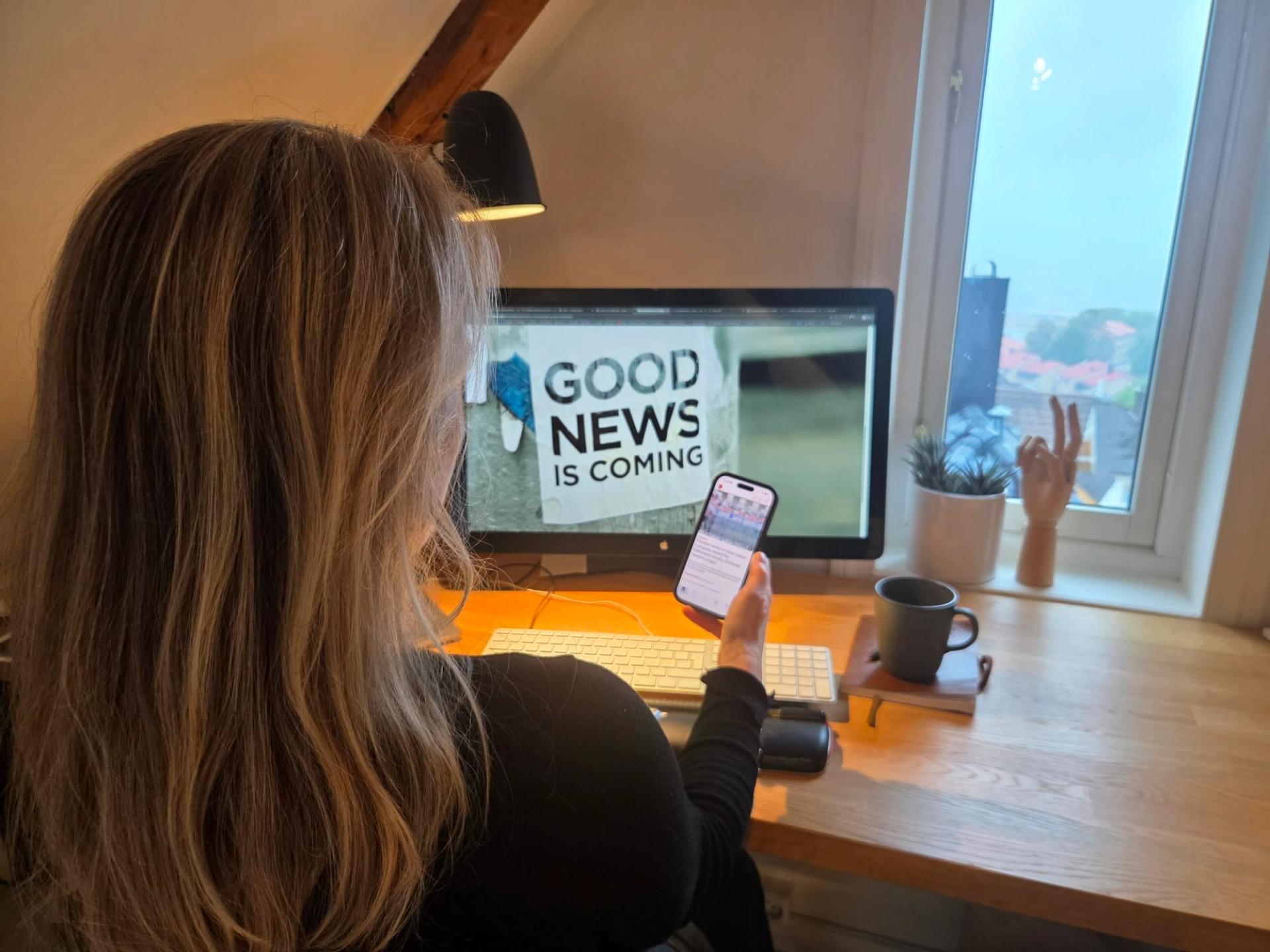 A woman sitting by a desk and reading news online.