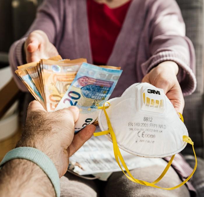 Woman holding money banknotes and surgical Hand Sanding Respirator procedure medical face mask during Coronavirus worldwide shortage of masks