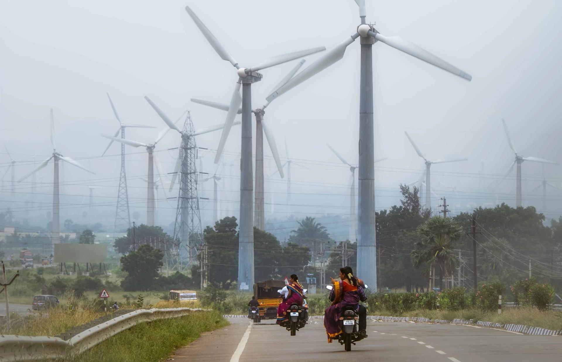 Motorcyclist on highway and wind turbines in India