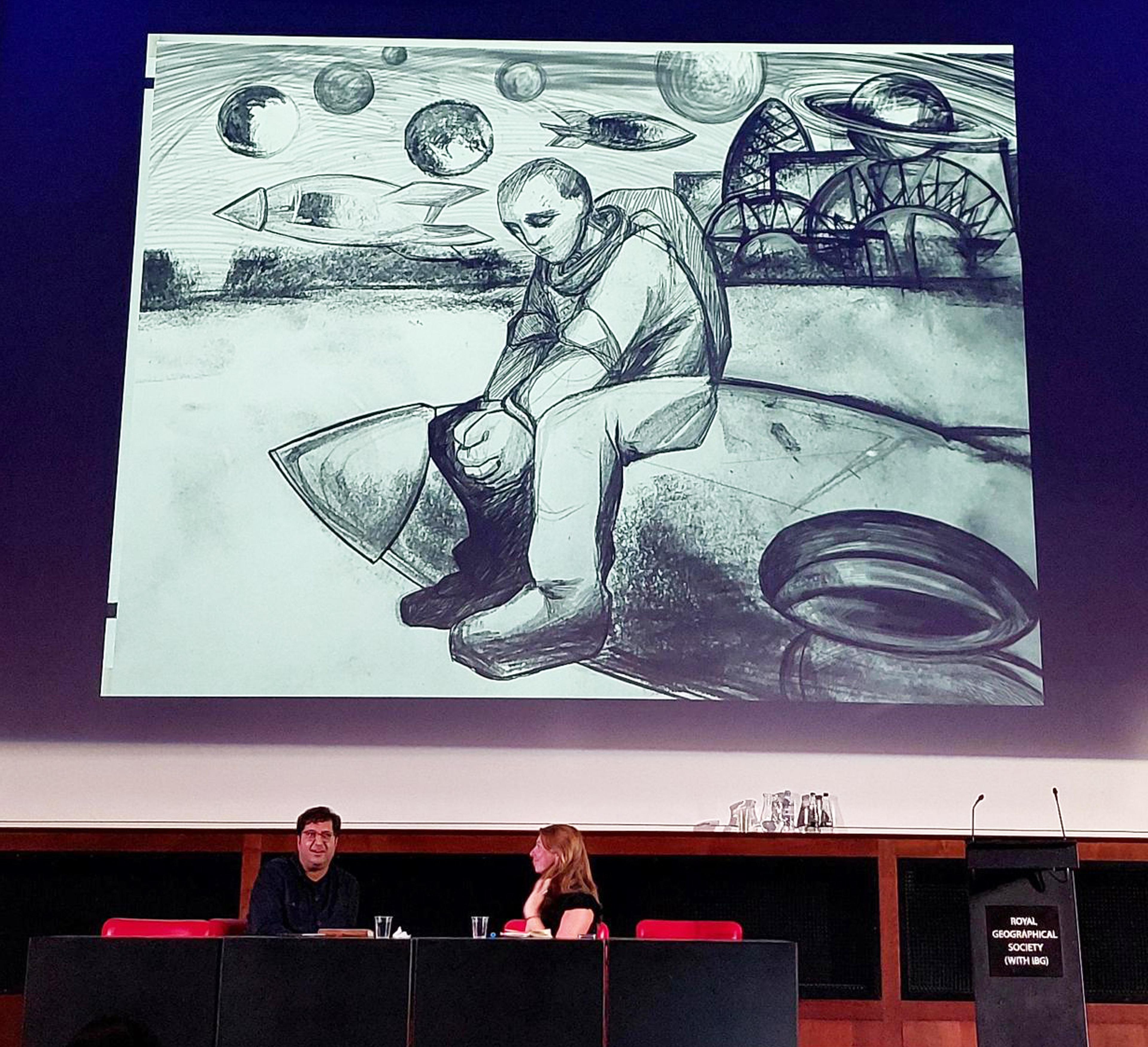 Two conference panelists sit beneath a large black-and white illustration of a sad-looking astronaut.