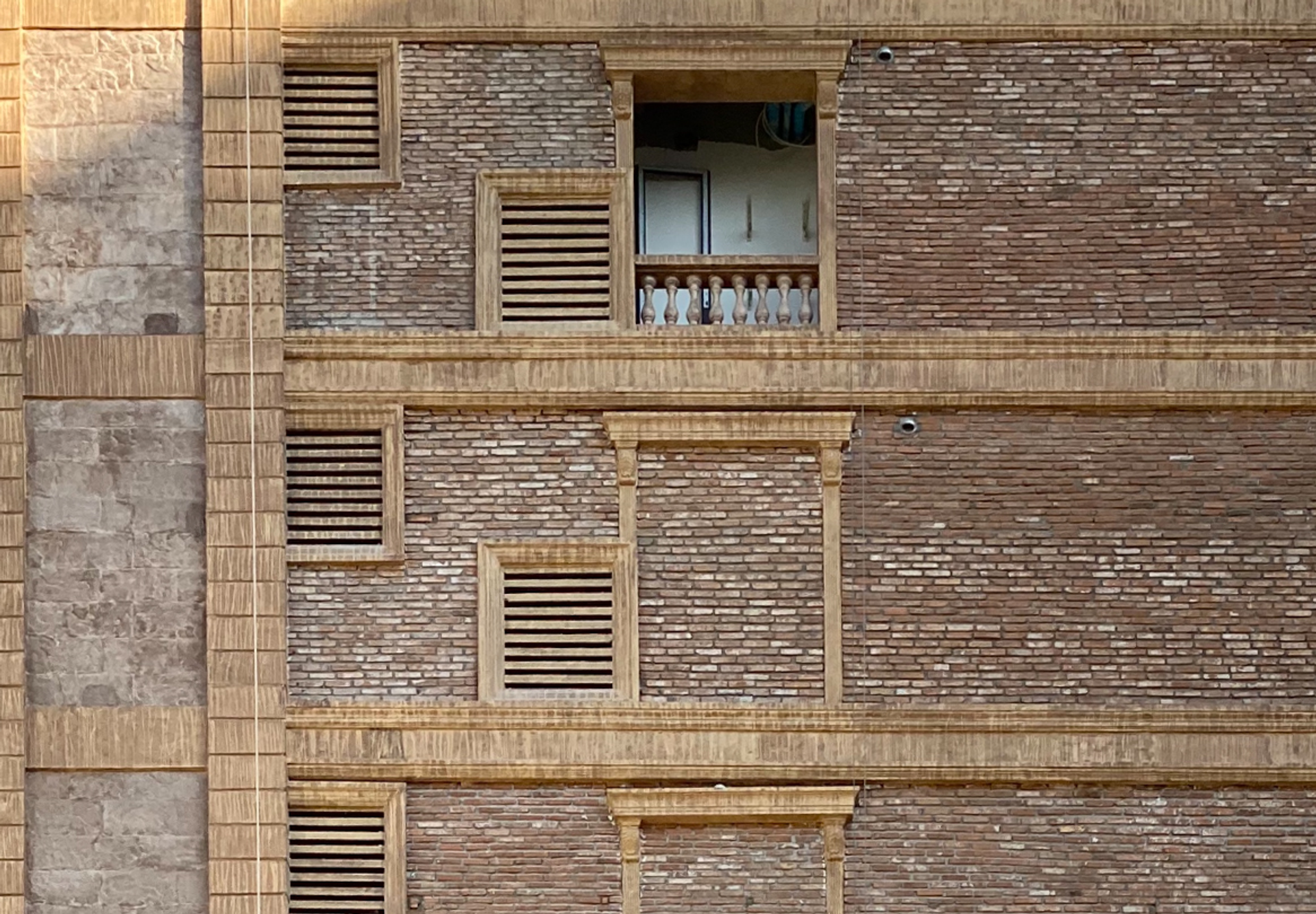 Tall brick building with several floors where only the top and bottom floor have an open window.