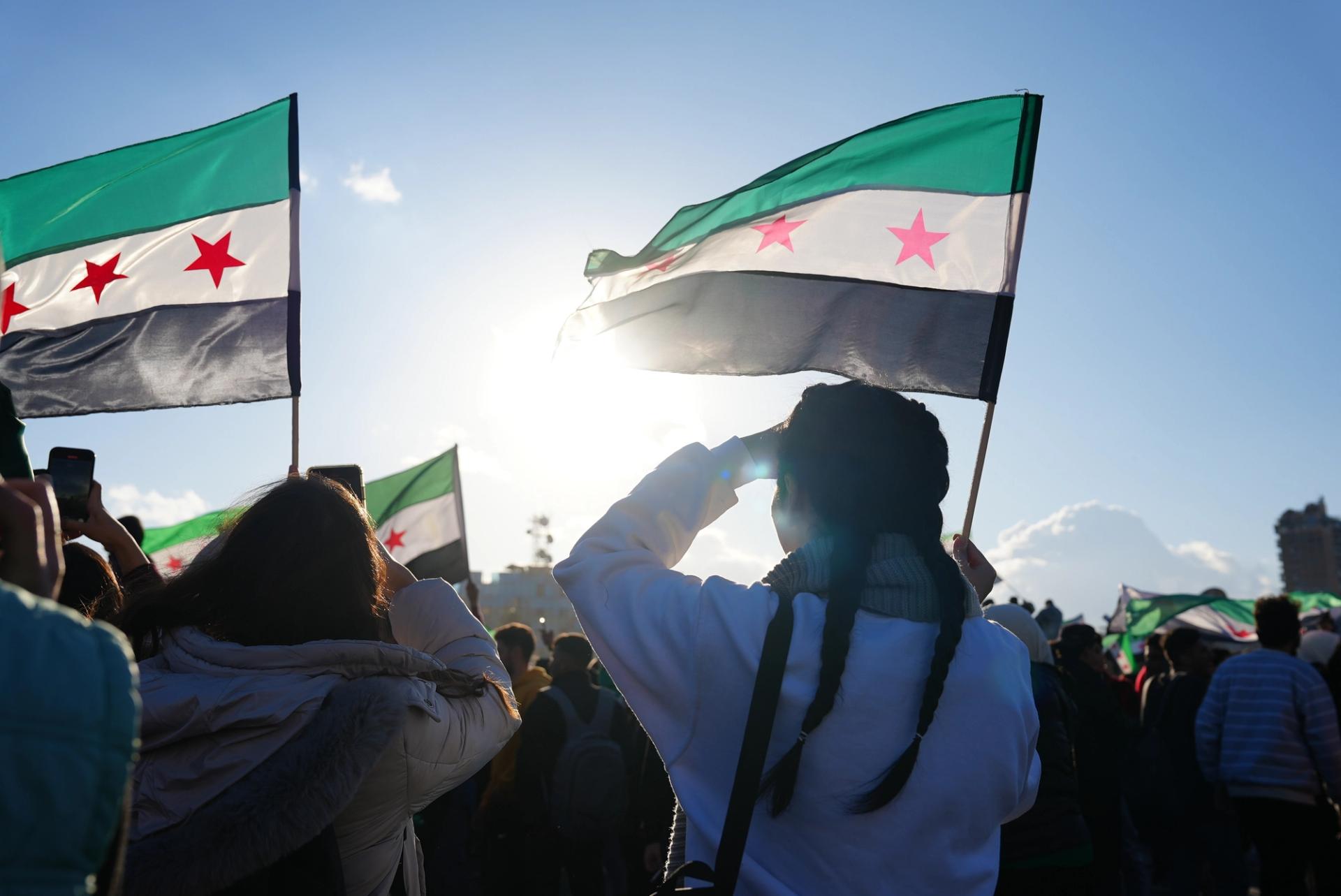 Civilians with Syrian flags celebrating the liberation of Syria.