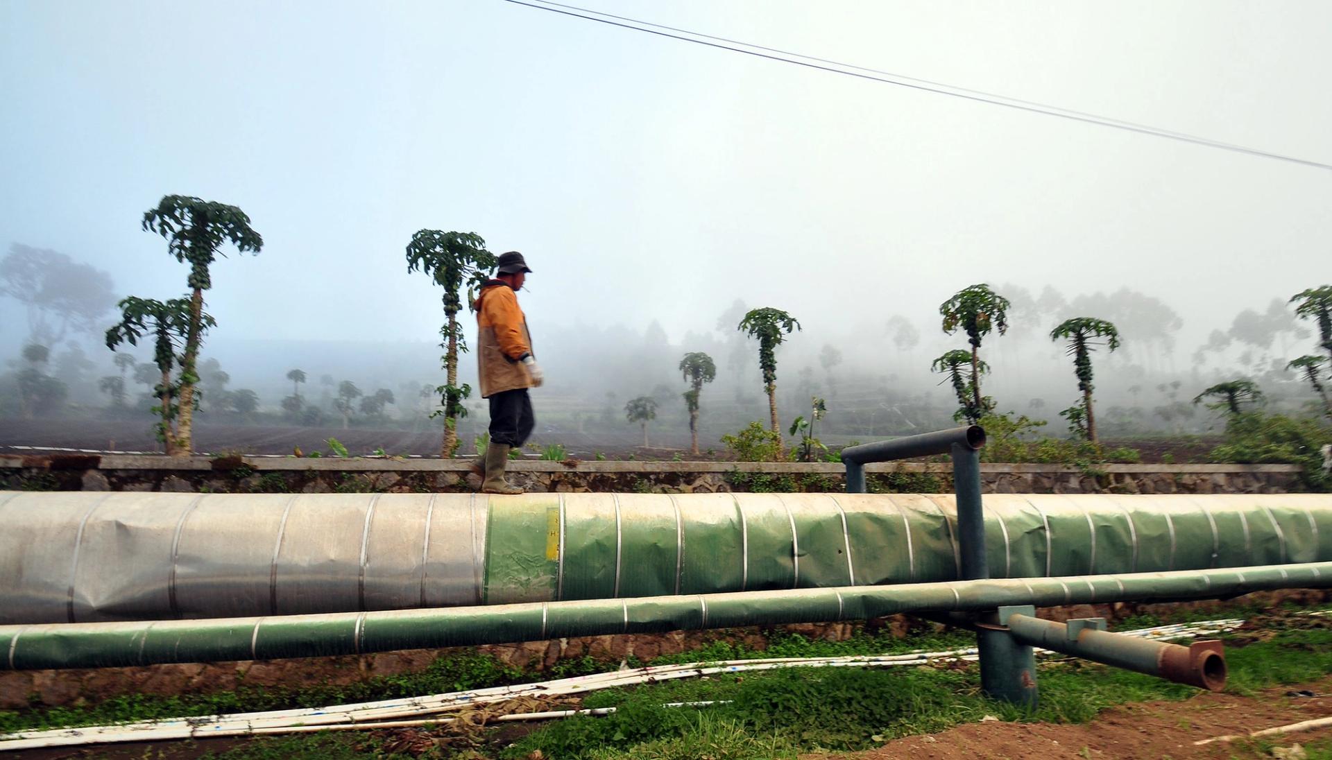 A man walking on a geothermal gas pipe in Indonesia