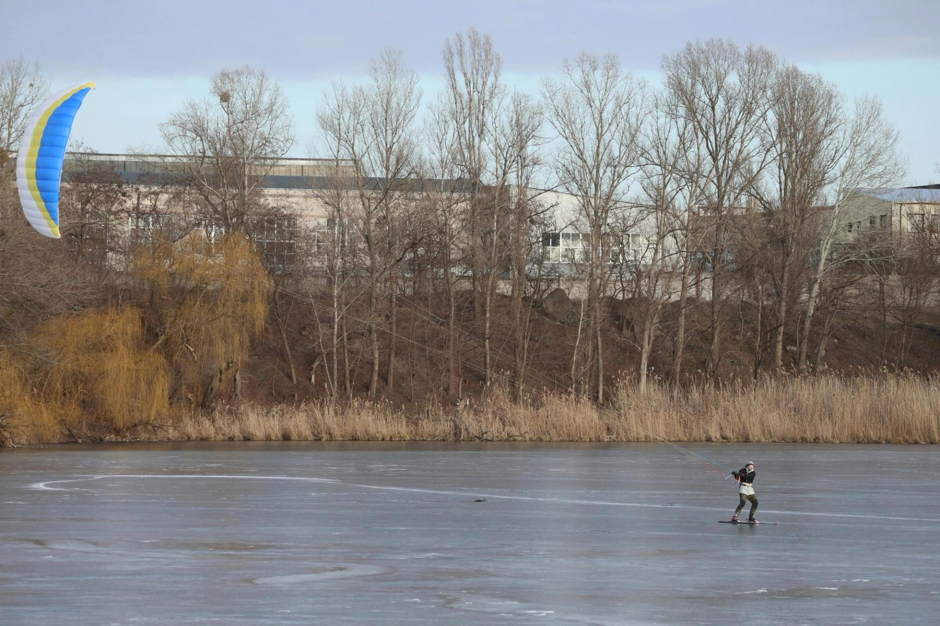 A person skating on a frozen lake while being dragged by a kite