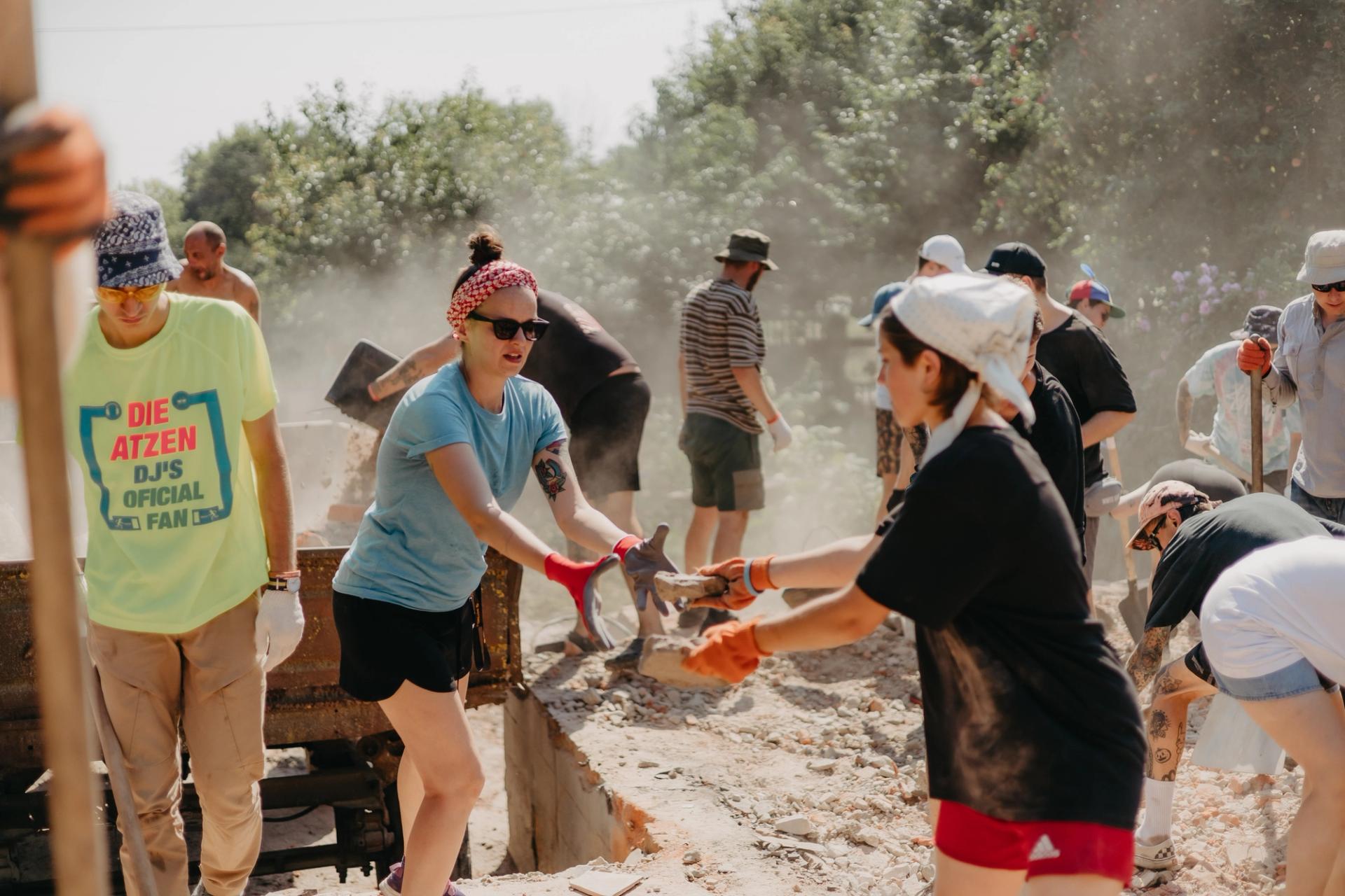 a group of volunteers is sorting through the rubble of a house destroyed by Russian missiles.