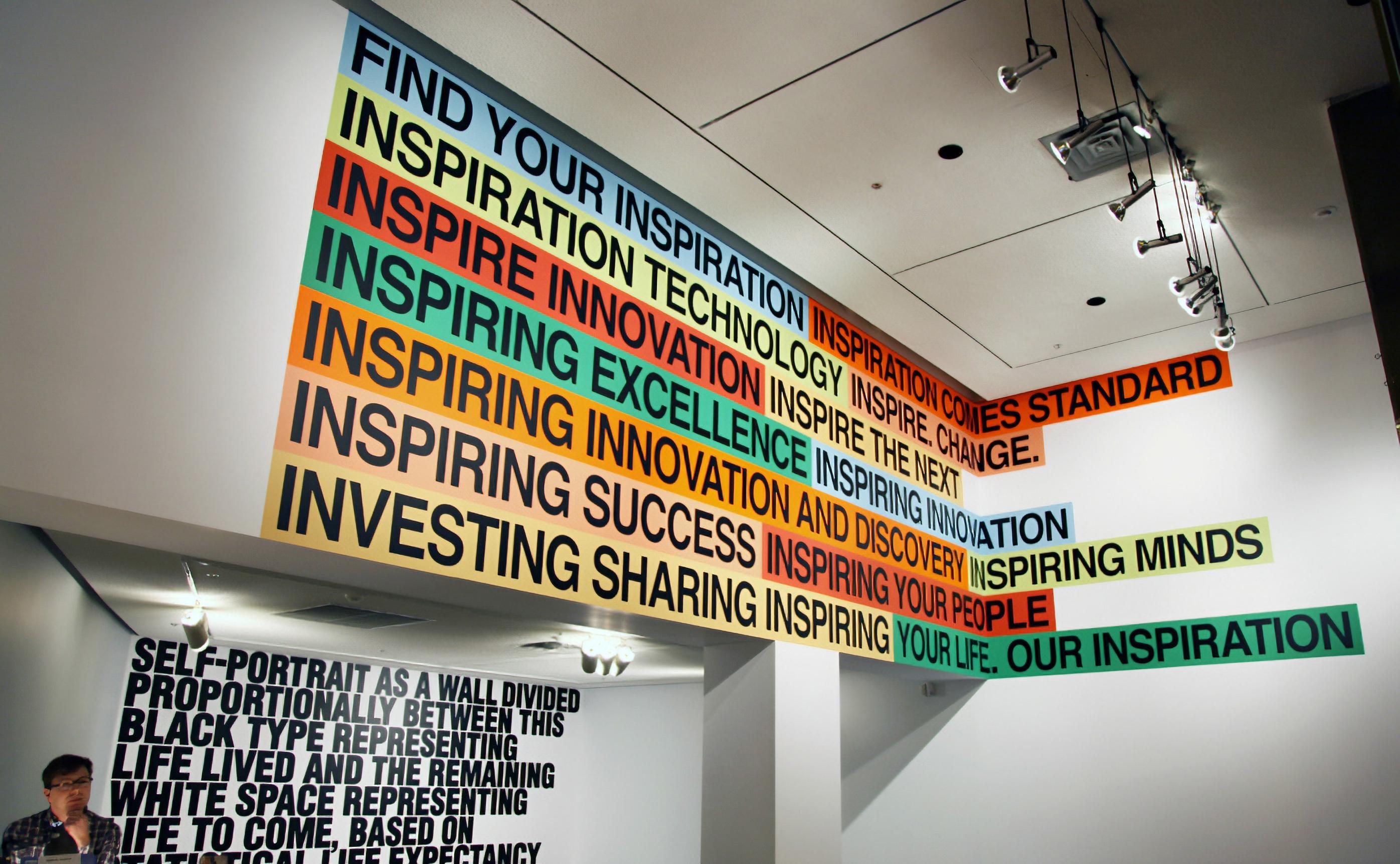 Colorful text strips on a white wall and ceiling, reading "FIND YOUR INSPIRATION", "INSPIRE INNOVATION", etc.