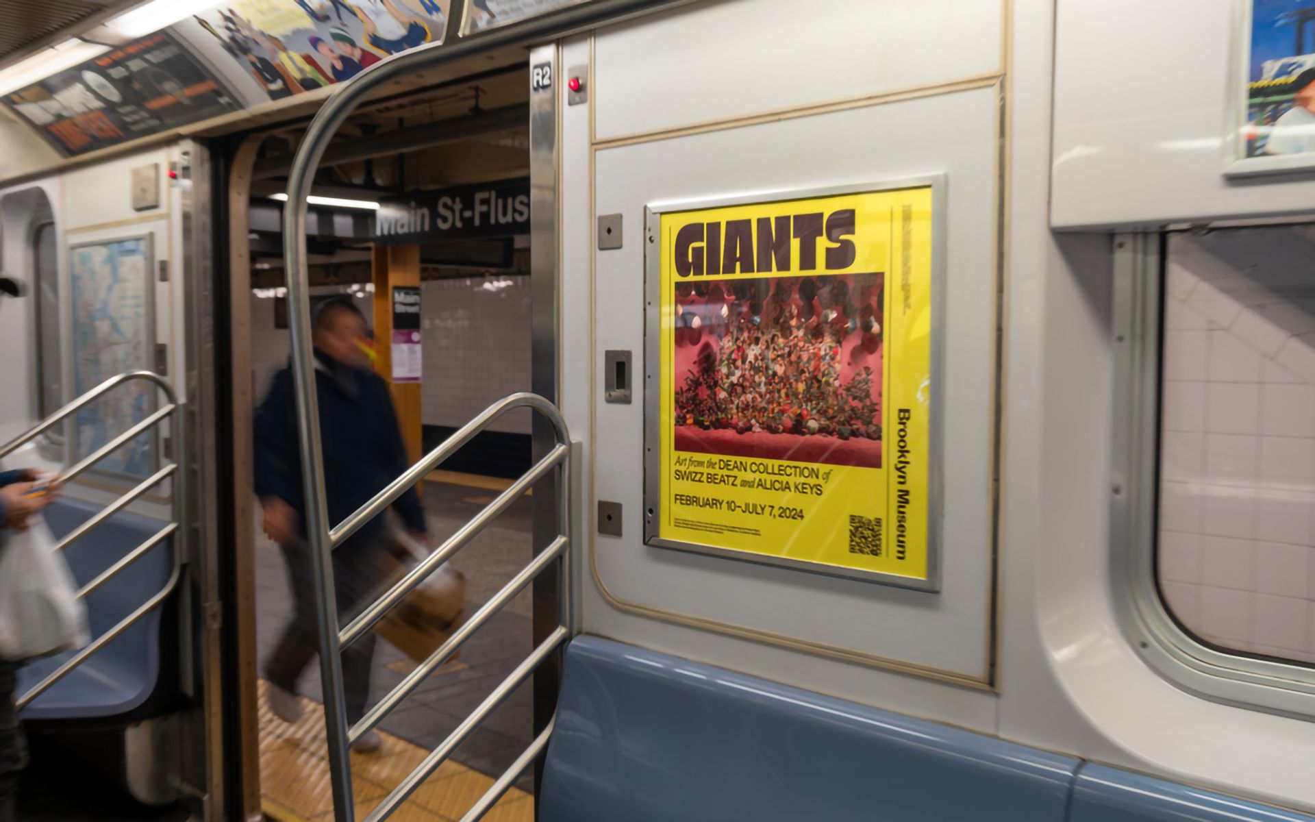Yellow poster for "GIANTS" Brooklyn Museum exhibit on subway car.