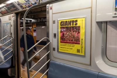 Yellow poster for "GIANTS" Brooklyn Museum exhibit on subway car.