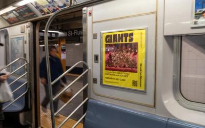 Yellow poster for "GIANTS" Brooklyn Museum exhibit on subway car.