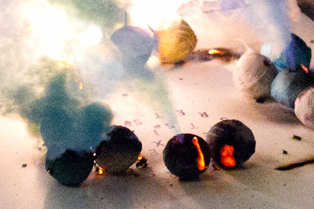 Burning firecrackers on a surface with scattered letters.