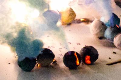 Burning firecrackers on a surface with scattered letters.