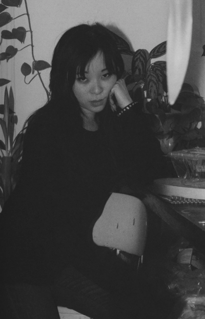 Black and white portrait of a young woman with dark hair, resting her head on her hand.