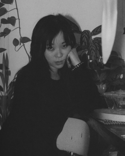 Black and white portrait of a young woman with dark hair, resting her head on her hand.