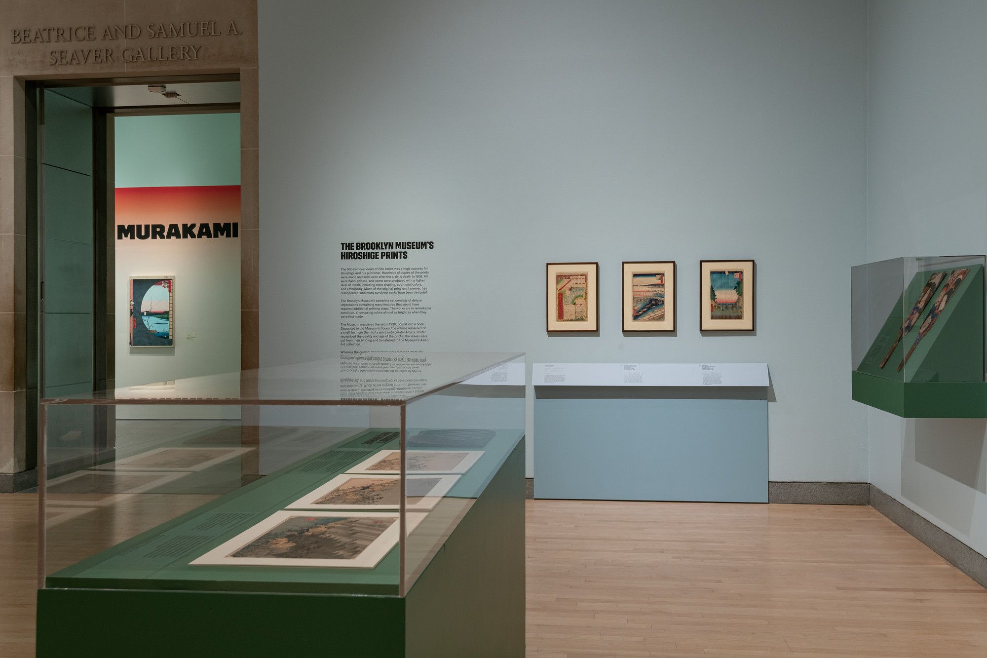 Murakami exhibit with prints in glass cases and on walls, gallery signage.
