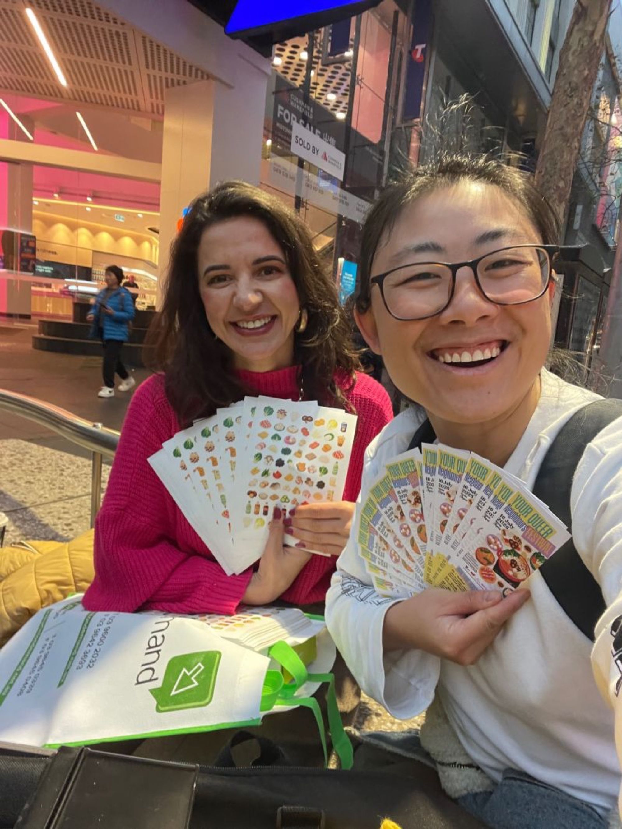Two people laughing while holding hot pot connection cards