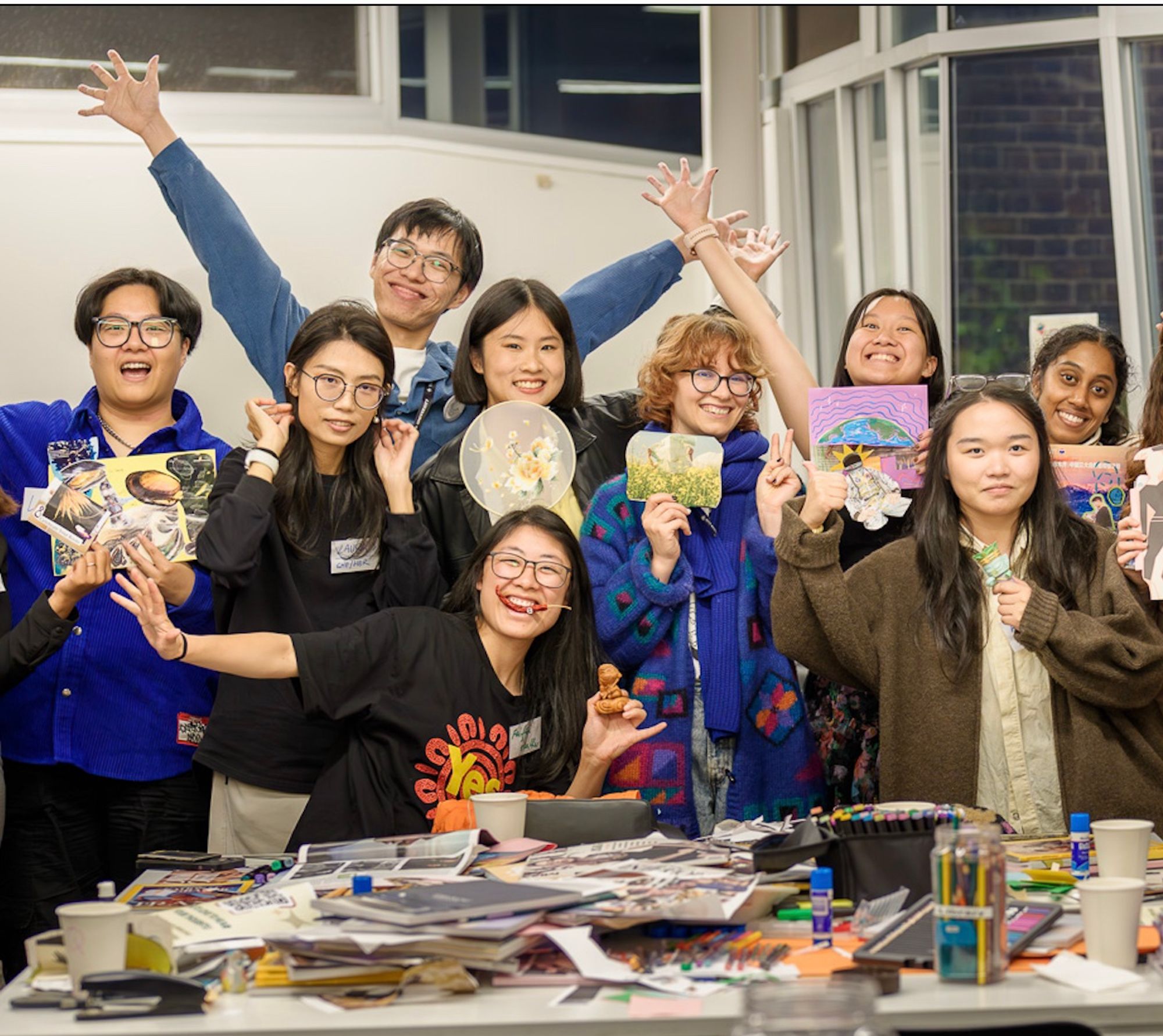 People cheering with the zines they made at a workshop