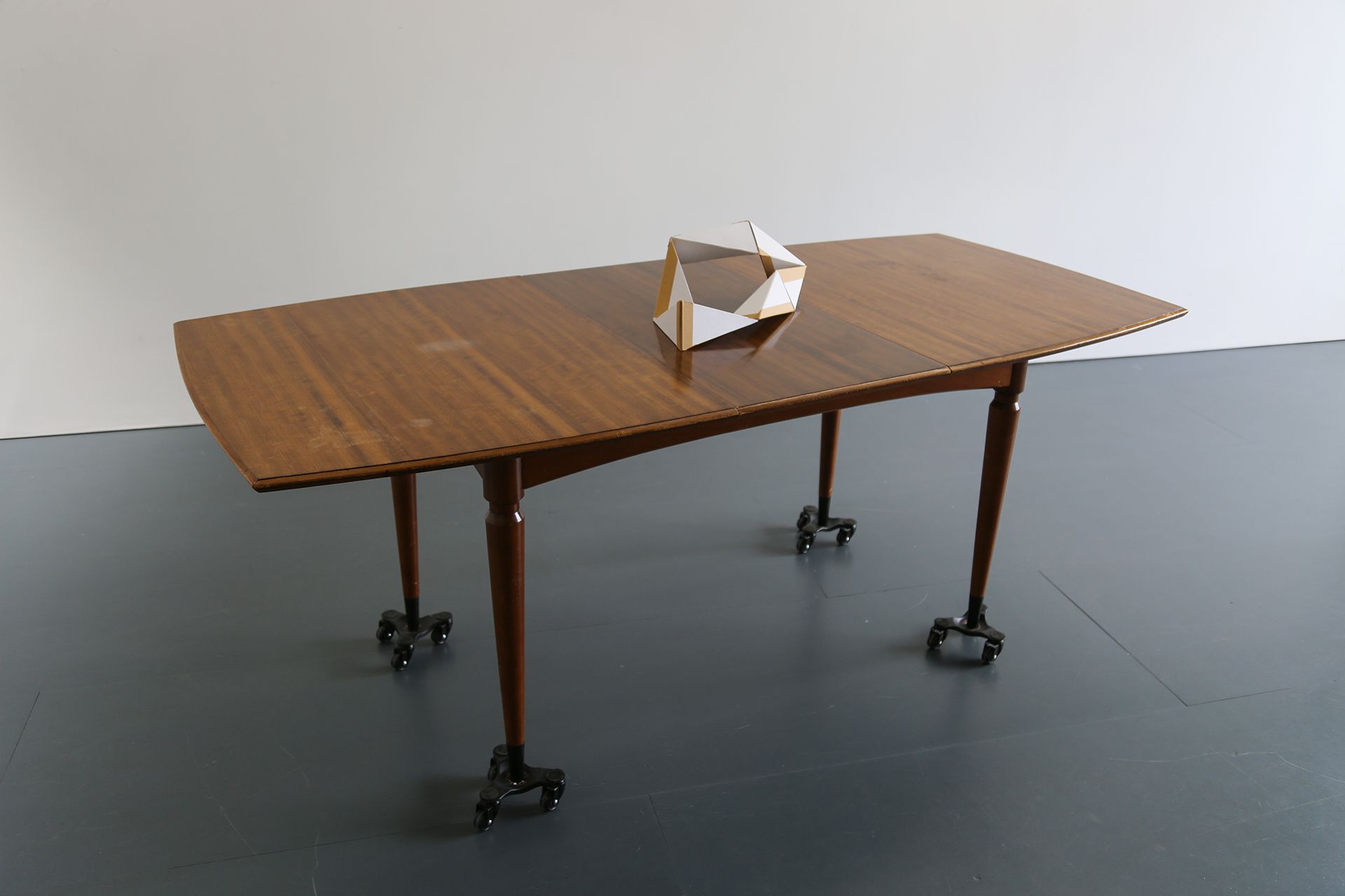 Lucy Gunning, Inheritance on Wheels, 2023. Mid 50s family table, wheels. With Props: Seven link moveable chain, 2023.