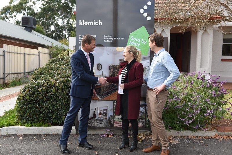 Matt Smith shaking hand of couple stand infront of klemich sign and house for sale