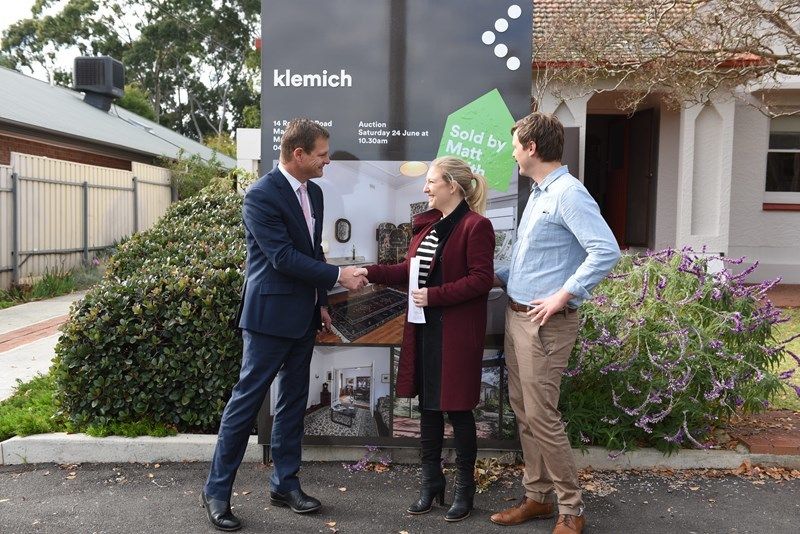 Matt Smith shaking hand of couple stand infront of klemich sign and house for sale 