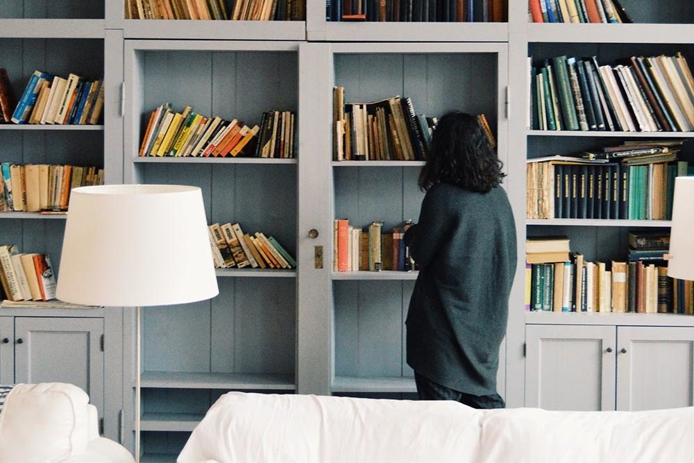 Woman in living room looking at bookshelf