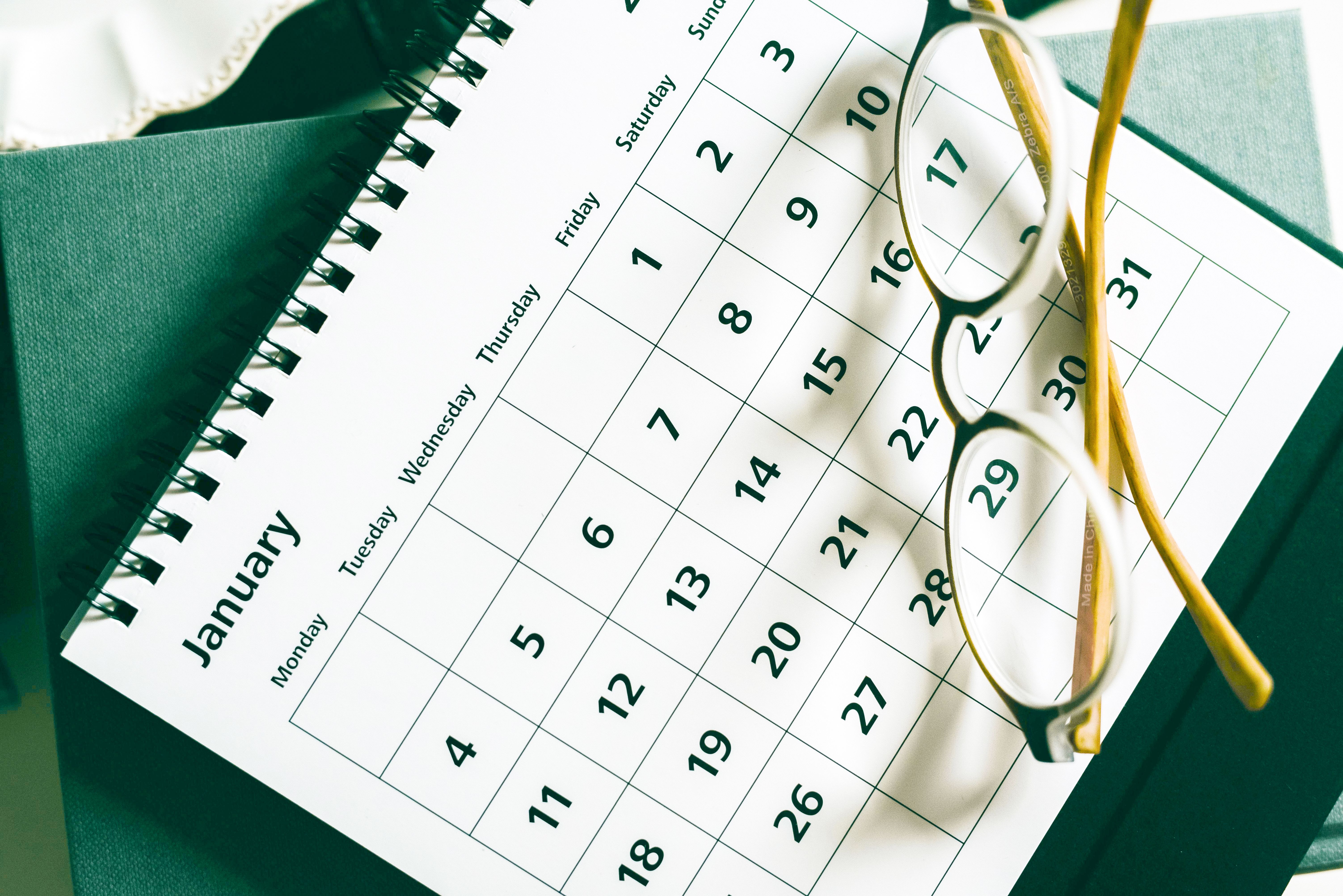 A flip calendar that shows the month of January, with a pair of reading glasses sitting on top