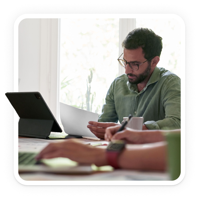 Man at table reviewing a document in front of a computer