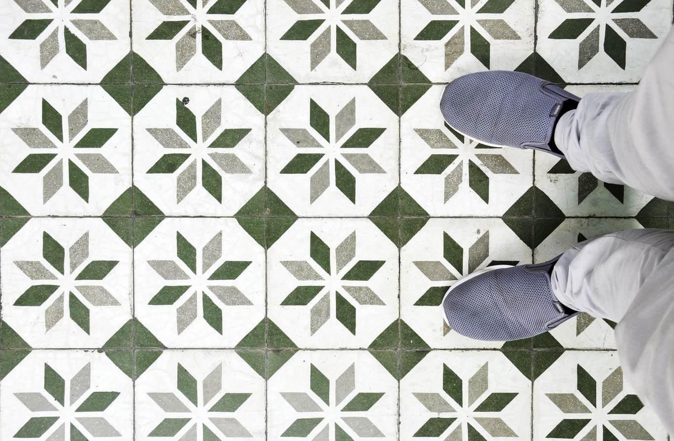 person in jeans and shoes standing on green mosaic tiled floor