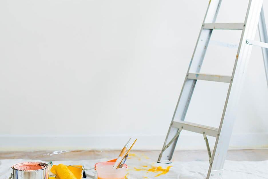 ladder in front of white wall with orange and yellow paint
