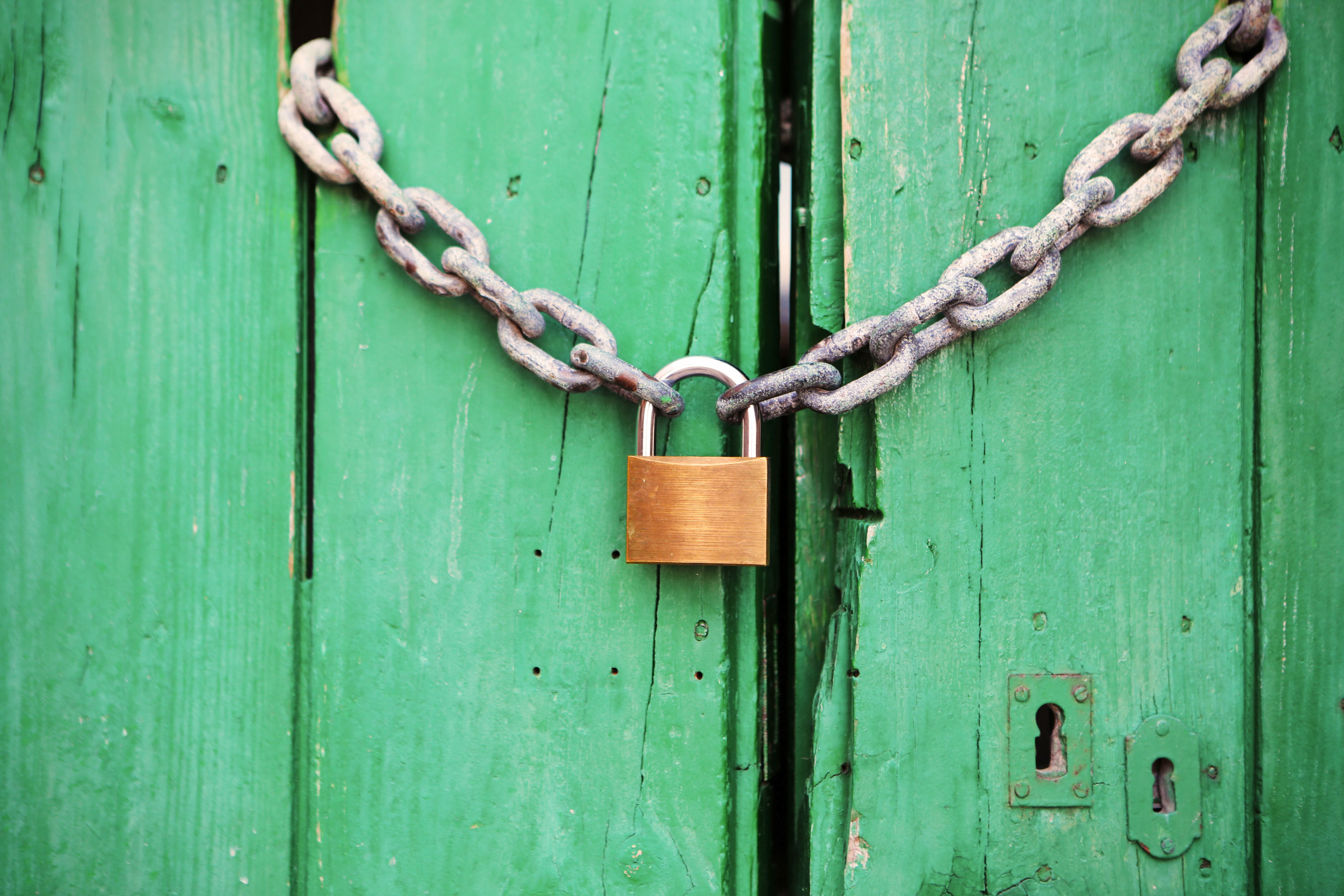 Green doors closed and barred by a thick chain and padlock.