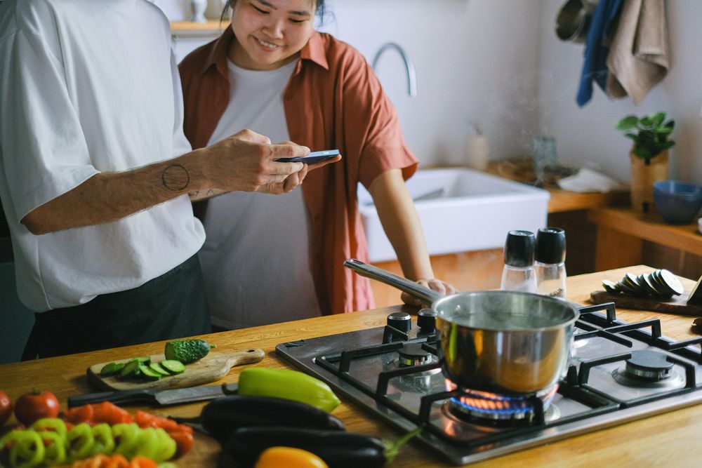 Person showing another person a video on phone in kitchen. Memes?