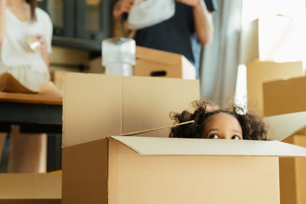 Young girl poking eyes out from behind a cardboard box