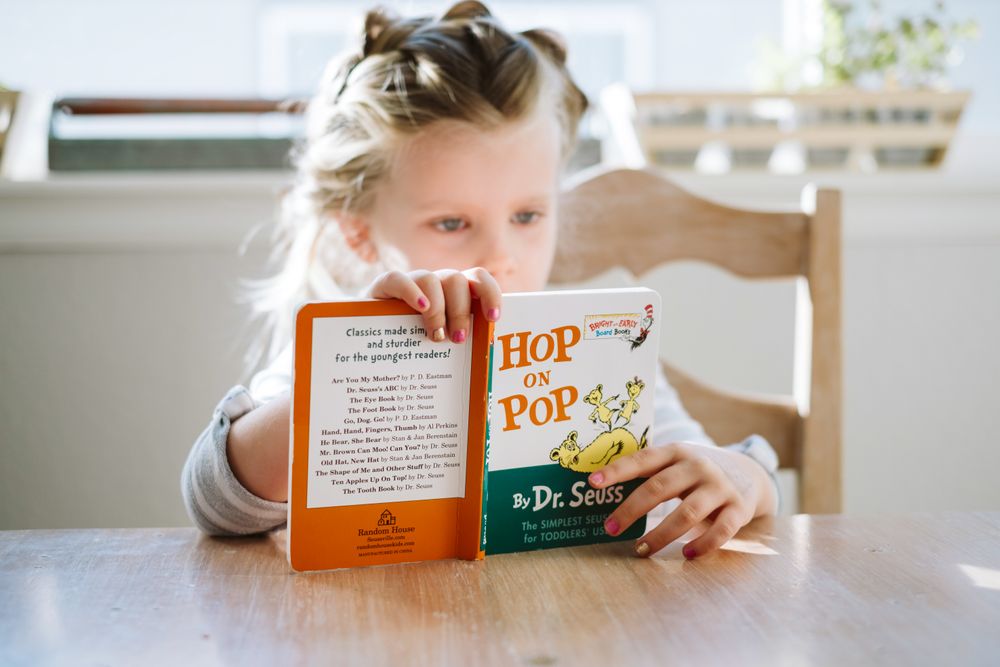 Young blonde girl reading Hop on Pop by Dr Seuss