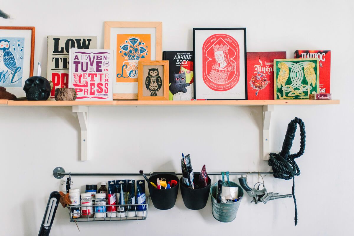 Shelf with coloured prints and handing storage below