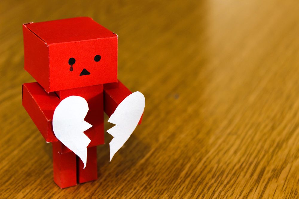 red robot with a tear holding broken heart