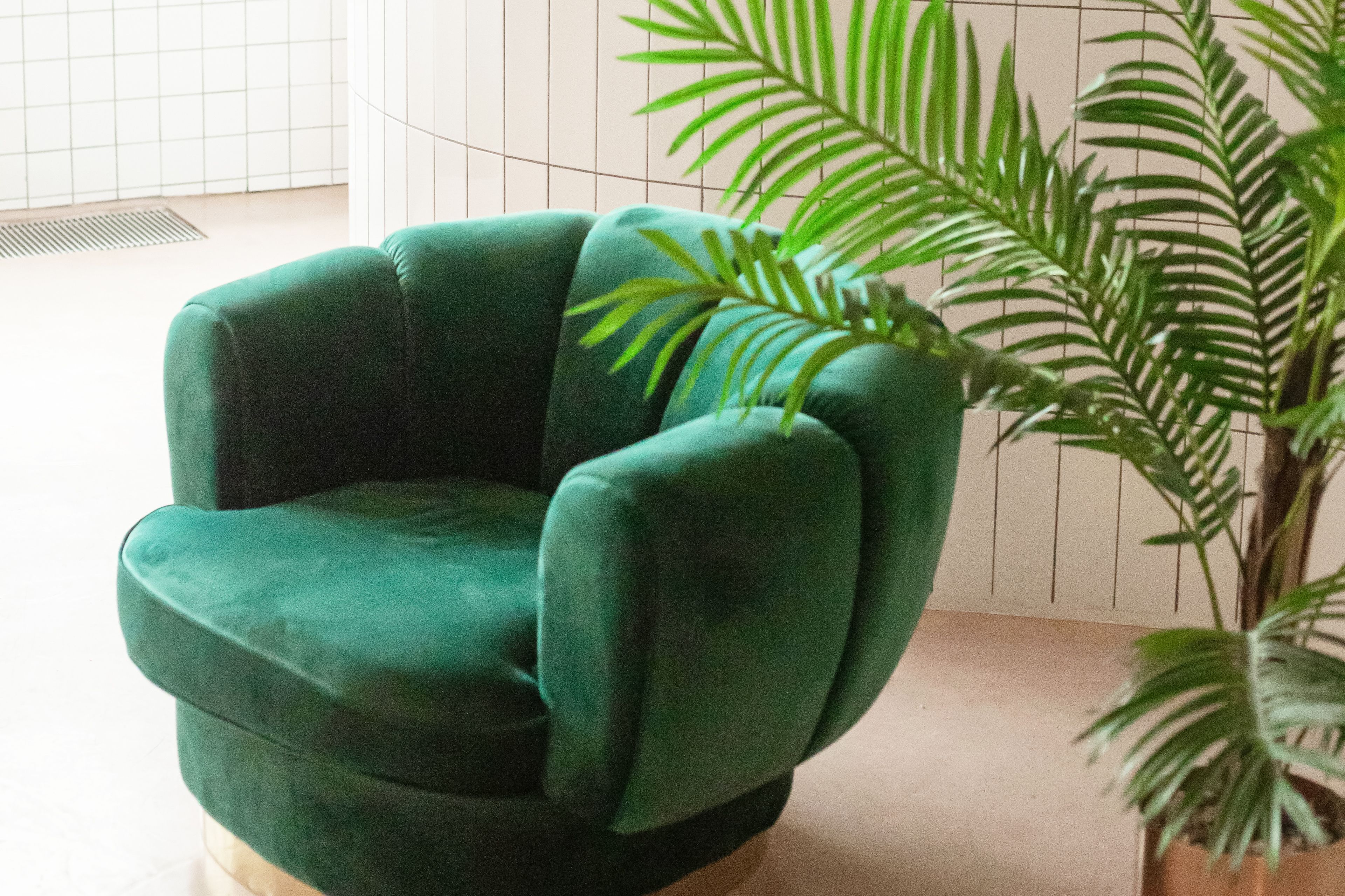 A luxury green velvet armchair with a fern in a contemporary setting.