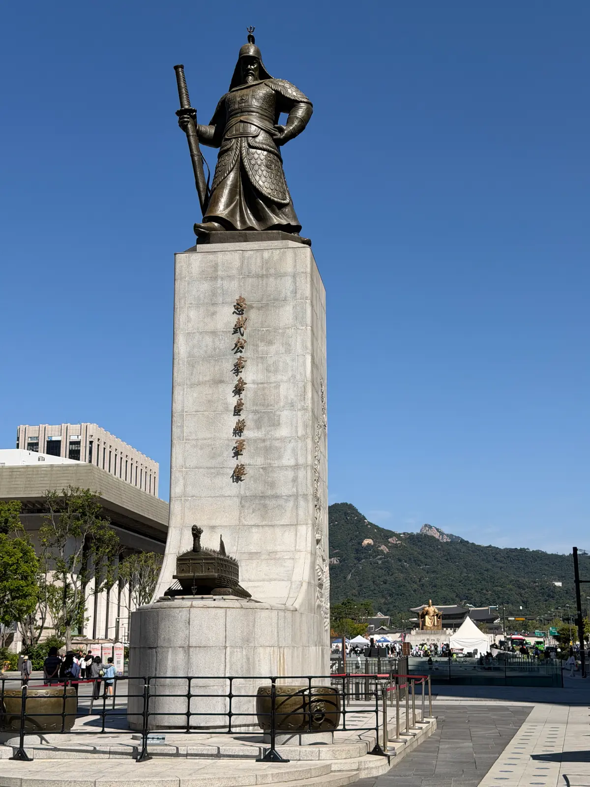 광화문광장 이순신 장군 동상, 좌대에 거북선 모형이 있고 뒤로 경복궁이 보인다