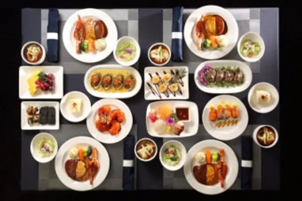 Overhead view of a curated Korean course meal with Hanwoo, sashimi, tempura, and banchan on a dark linen table