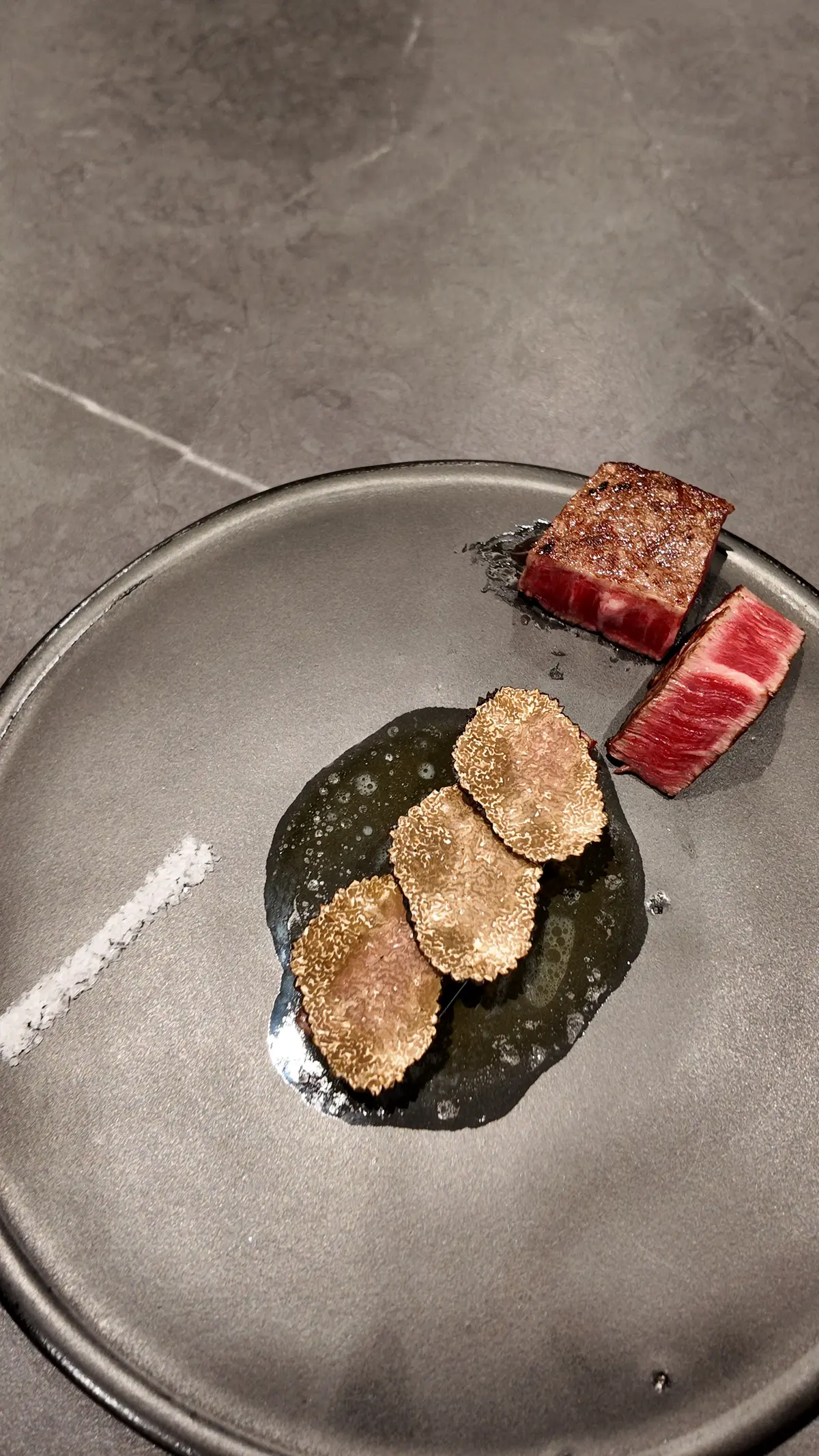 Seared Hanwoo cubes paired with seared beef slices on a glass plate over marble at KUT Seoul omakase