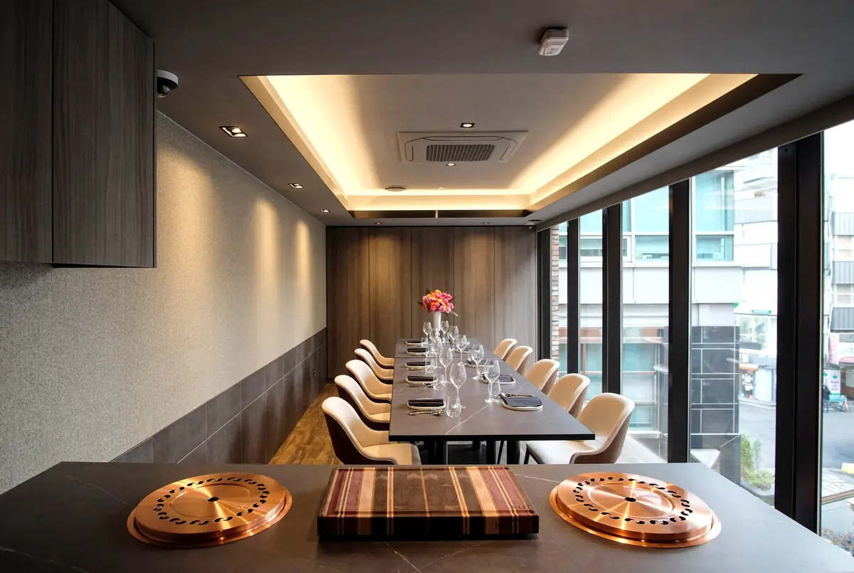 KUT Seoul private dining room with copper grills, long marble table, velvet chairs, and Jongno city views