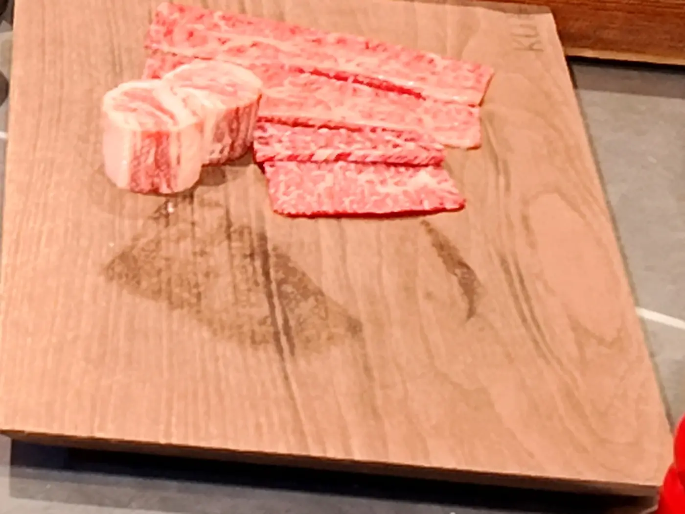 Sliced four-week wet-aged BMS no.9 Hanwoo on a wooden board at KUT SEOUL, Jongno, showing fine marbling