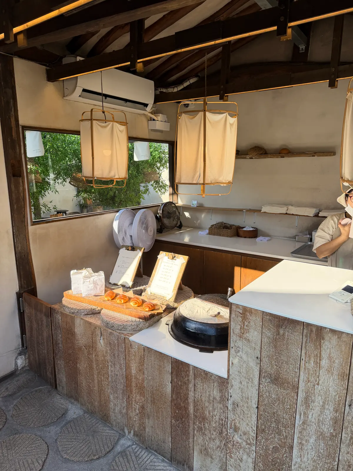 焼きたてのクロワッサンと伝統的な石臼が置かれた益善洞の韓屋ベーカリーカウンター