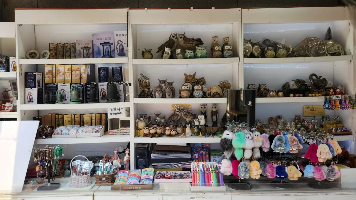 陶磁器のフクロウ、青銅の鈴、屏風、ふわふわのキーホルダーが並ぶソウルの韓国土産物の屋台