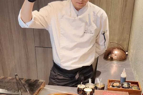 KUT Seoul主厨兼老板Benjamin Kang在omakase吧台的铜制烤炉上为韩牛调味